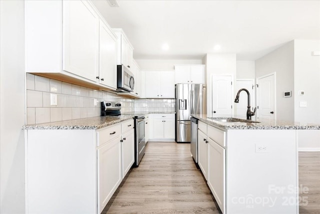 kitchen featuring light wood-style floors, appliances with stainless steel finishes, backsplash, and a sink