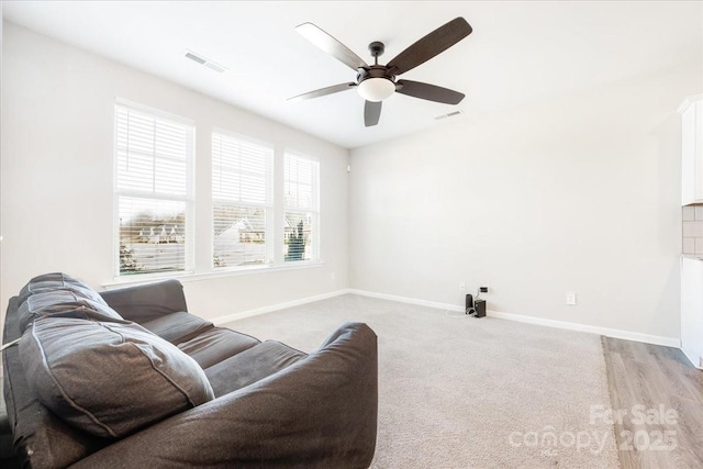 living room featuring baseboards, visible vents, and a ceiling fan