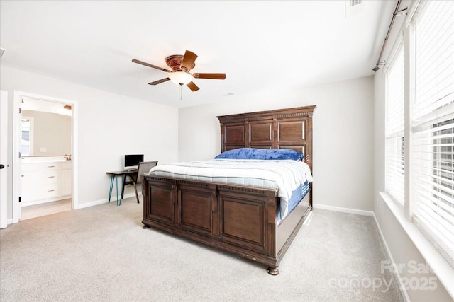 bedroom with light carpet, ensuite bath, multiple windows, and baseboards