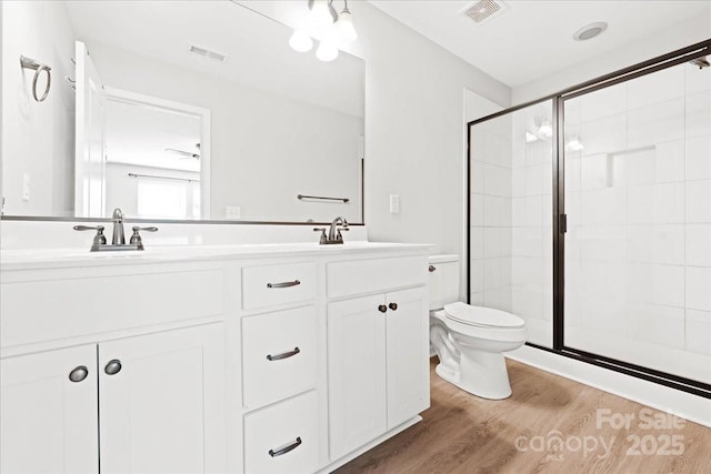 full bathroom featuring a sink, a stall shower, visible vents, and wood finished floors