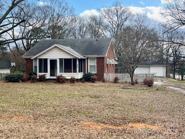 view of front of property featuring a garage, brick siding, an outdoor structure, fence, and a front lawn