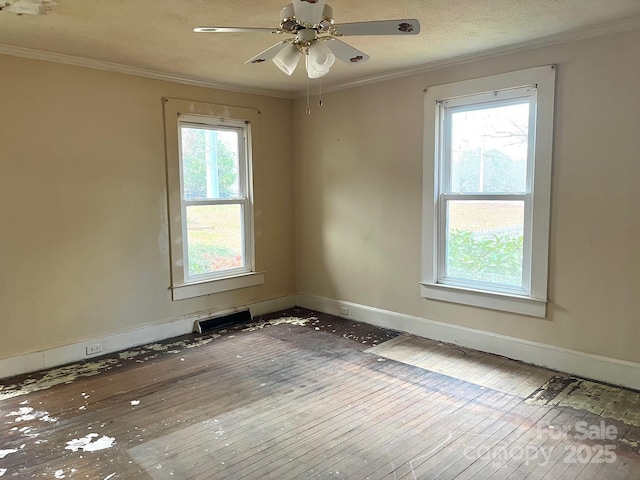 spare room featuring baseboards, wood-type flooring, and crown molding