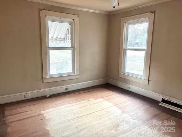 unfurnished room featuring crown molding, light wood finished floors, baseboards, and a healthy amount of sunlight