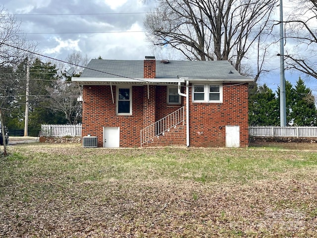 rear view of property with brick siding, fence, a chimney, and central air condition unit