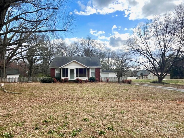 view of front of home featuring a front yard, brick siding, fence, and an attached garage