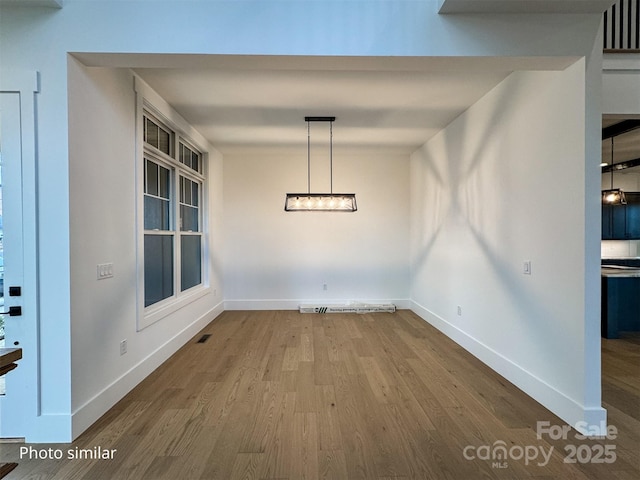 unfurnished dining area featuring visible vents, baseboards, and wood finished floors