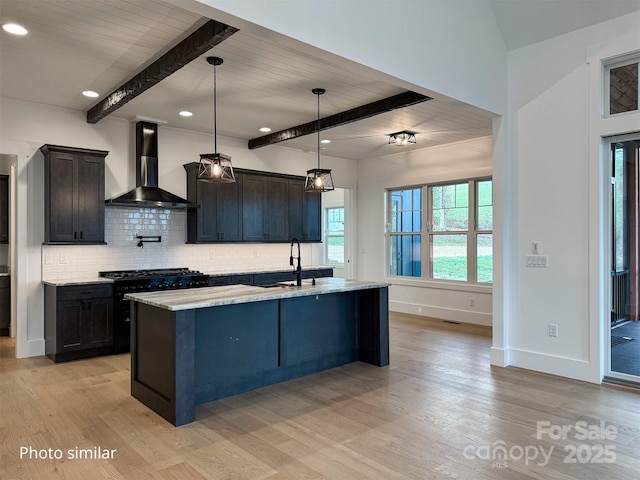 kitchen with a sink, light wood-style floors, backsplash, beam ceiling, and wall chimney exhaust hood