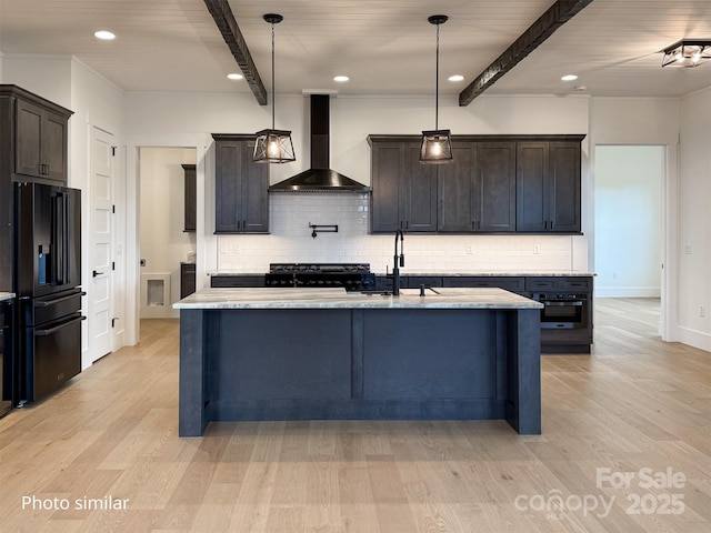 kitchen with light wood finished floors, a sink, wall chimney range hood, beamed ceiling, and black appliances