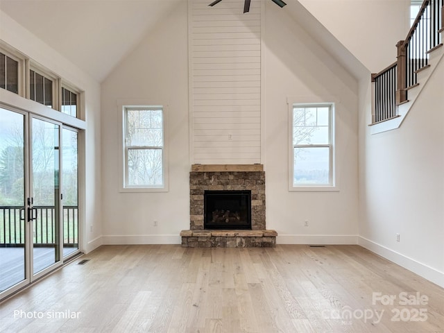 unfurnished living room with high vaulted ceiling, a fireplace, plenty of natural light, and wood finished floors