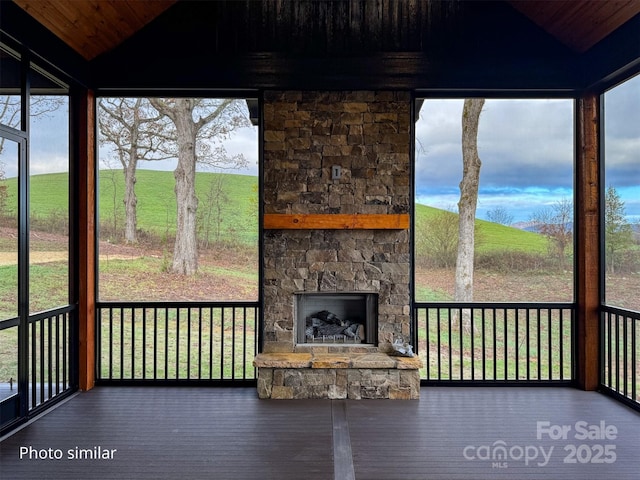 unfurnished sunroom with an outdoor stone fireplace and vaulted ceiling