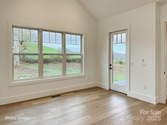 doorway with lofted ceiling, visible vents, light wood-style flooring, and baseboards