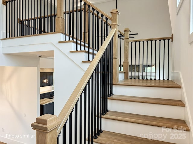 stairs featuring wood finished floors and a towering ceiling