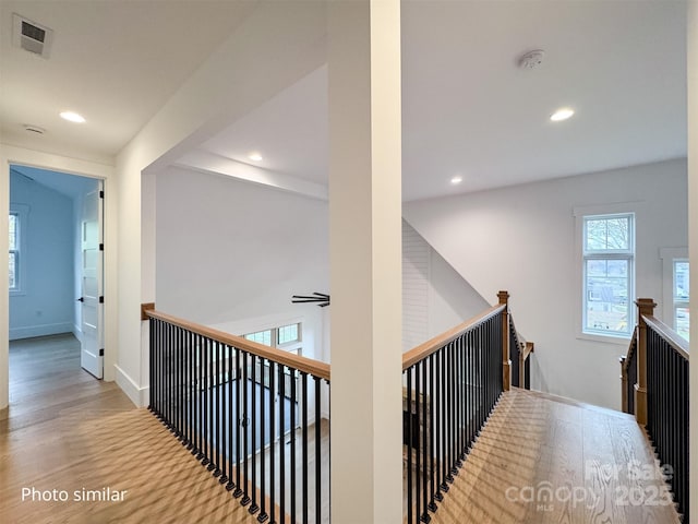 hall with recessed lighting, visible vents, an upstairs landing, wood finished floors, and baseboards