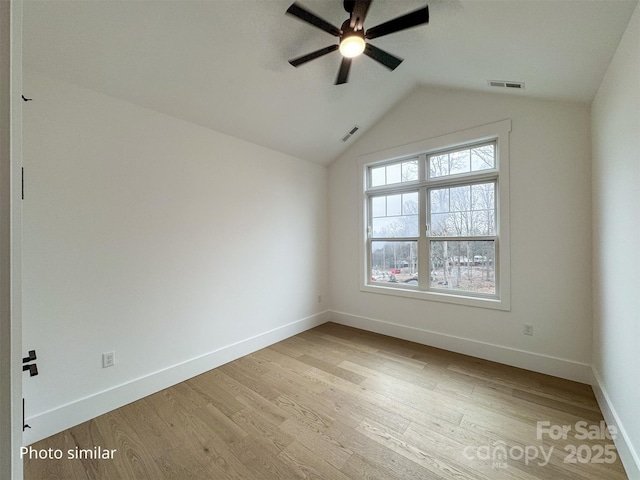 unfurnished room featuring lofted ceiling, visible vents, baseboards, and wood finished floors