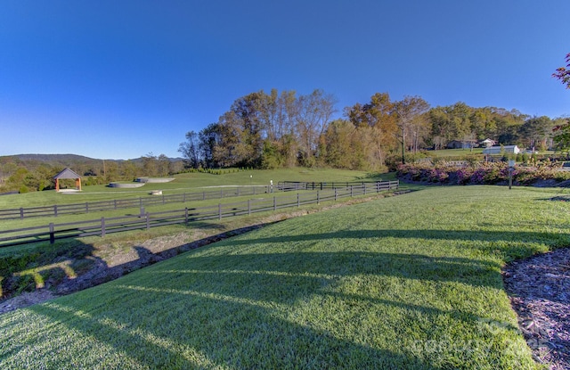 view of yard with fence, a mountain view, and a rural view