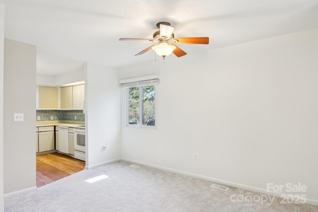 interior space with visible vents, baseboards, light colored carpet, and a ceiling fan