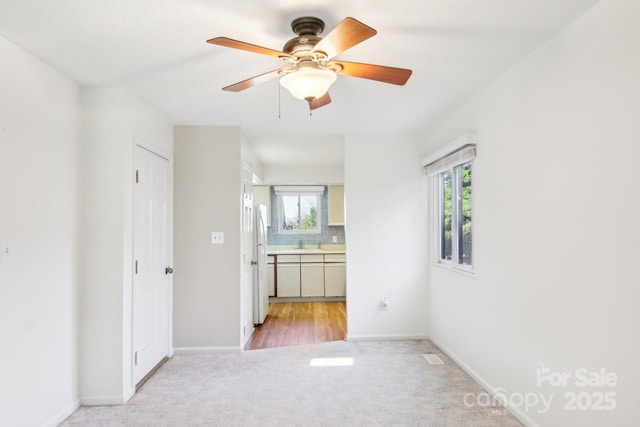 empty room featuring baseboards, light colored carpet, and a healthy amount of sunlight