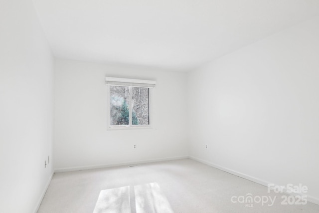 carpeted spare room featuring baseboards