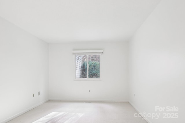 empty room featuring light colored carpet and baseboards