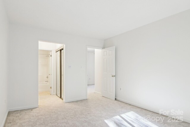 unfurnished bedroom with baseboards, carpet floors, and ensuite bath