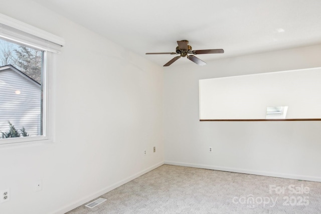 carpeted spare room featuring baseboards, visible vents, and ceiling fan