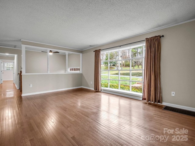 unfurnished living room featuring hardwood / wood-style flooring, a healthy amount of sunlight, and visible vents