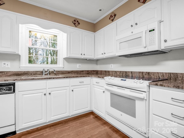 kitchen with dark stone counters, white cabinets, crown molding, and white appliances