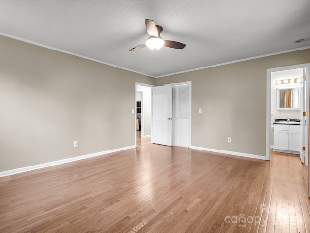unfurnished bedroom with light wood finished floors, baseboards, crown molding, and ensuite bath