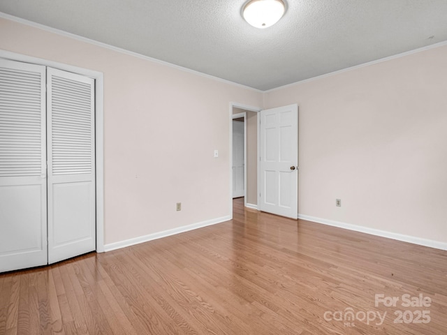 unfurnished bedroom with light wood-style flooring, ornamental molding, and baseboards