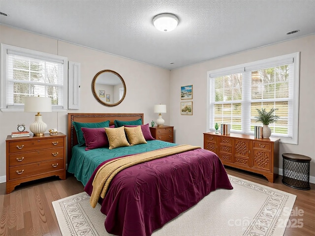 bedroom with light wood-style flooring, baseboards, and a textured ceiling