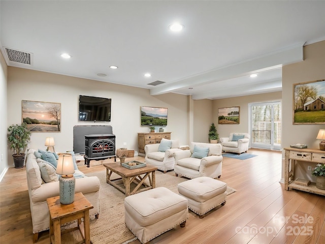 living area featuring visible vents, a wood stove, recessed lighting, and light wood-type flooring