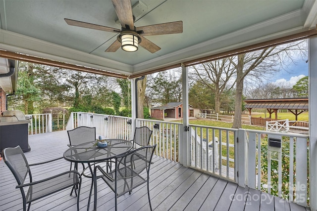 wooden deck with a ceiling fan, outdoor dining space, an outbuilding, and a shed