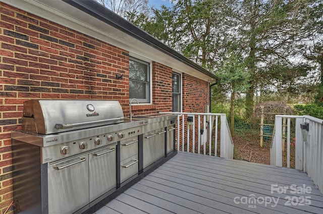 wooden deck with exterior kitchen, a sink, and area for grilling