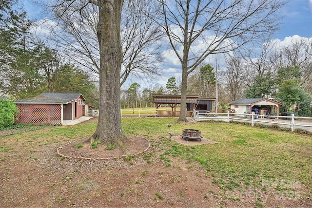 view of yard with an outdoor fire pit, fence, and an outbuilding