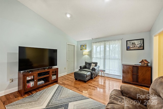 living area featuring lofted ceiling, baseboards, and hardwood / wood-style floors