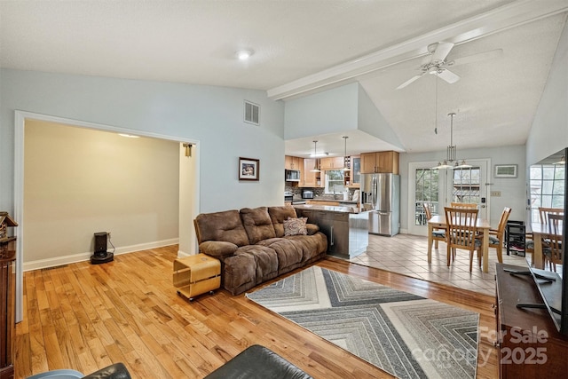 living area with light wood finished floors, visible vents, baseboards, lofted ceiling with beams, and ceiling fan