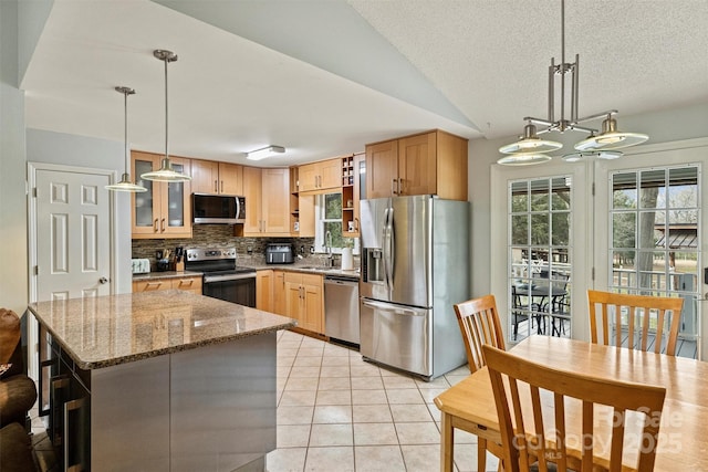 kitchen with stone counters, light tile patterned floors, stainless steel appliances, decorative backsplash, and a healthy amount of sunlight