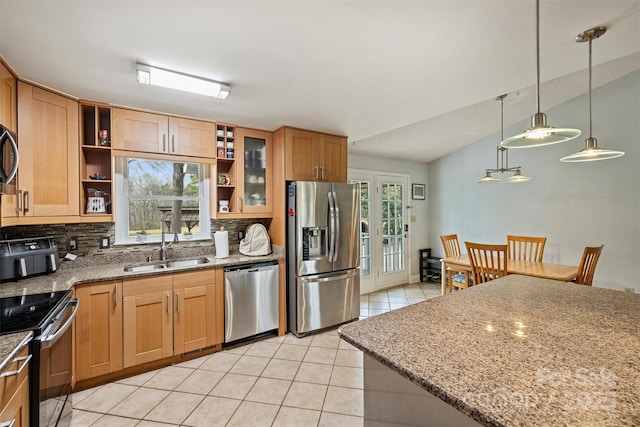 kitchen with stainless steel appliances, a sink, light stone counters, and light tile patterned floors