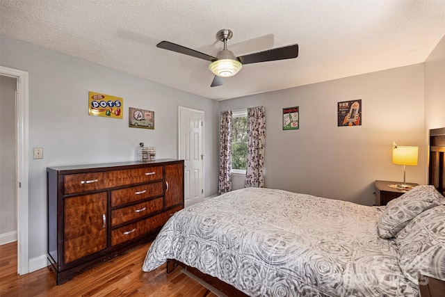 bedroom featuring a textured ceiling, wood finished floors, a ceiling fan, and baseboards