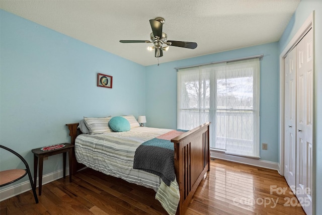 bedroom featuring baseboards, a ceiling fan, hardwood / wood-style floors, a textured ceiling, and a closet