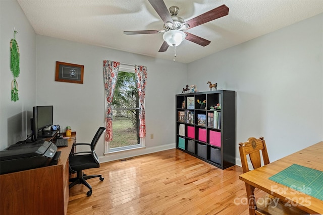 home office featuring a textured ceiling, visible vents, a ceiling fan, baseboards, and hardwood / wood-style floors