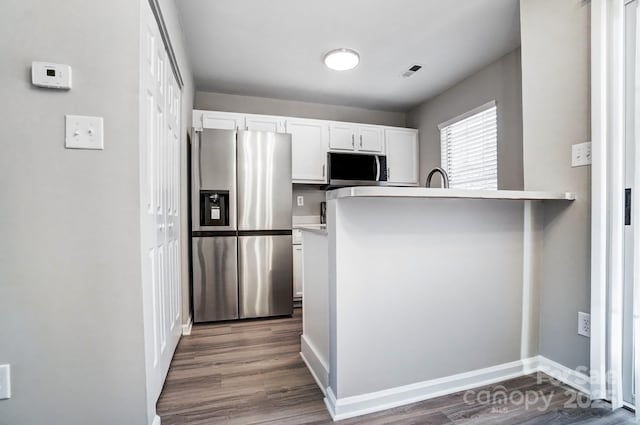 kitchen featuring visible vents, white cabinets, appliances with stainless steel finishes, dark wood-style flooring, and a peninsula