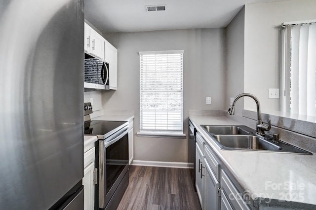 kitchen featuring dark wood-style flooring, visible vents, appliances with stainless steel finishes, a sink, and baseboards