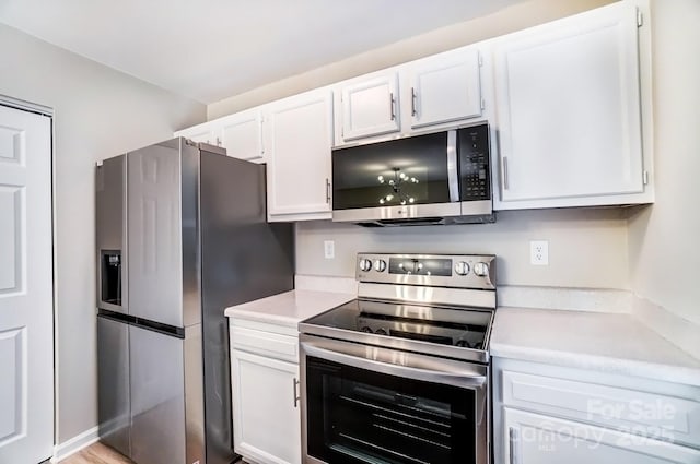 kitchen with stainless steel appliances, light countertops, and white cabinets