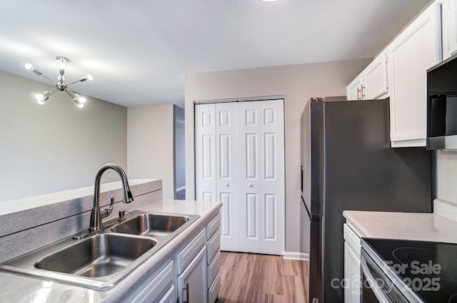 kitchen featuring a sink, light wood-style floors, white cabinets, light countertops, and stainless steel electric range oven