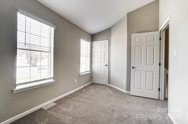 unfurnished bedroom with carpet floors, lofted ceiling, visible vents, and baseboards