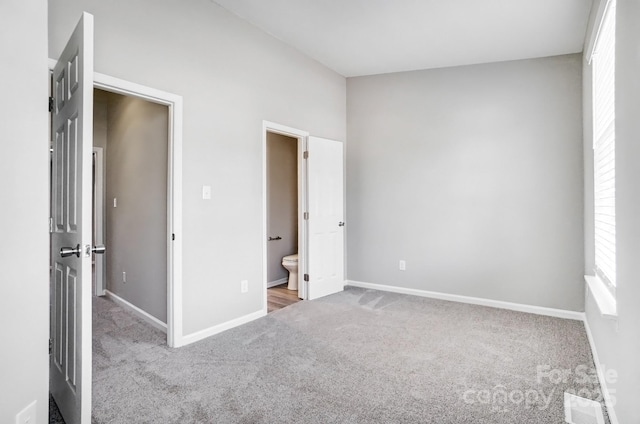 unfurnished bedroom featuring carpet, visible vents, connected bathroom, and baseboards