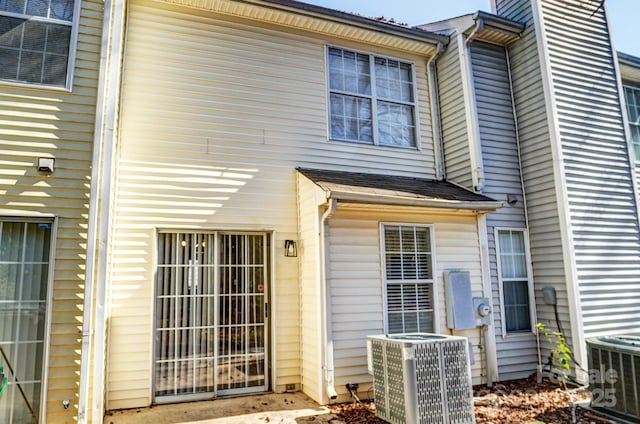 property entrance featuring a shingled roof and cooling unit