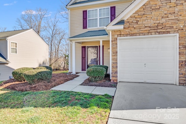 view of front of house featuring stone siding, driveway, and an attached garage