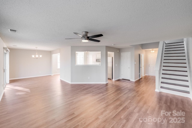 unfurnished living room featuring visible vents, baseboards, stairs, light wood-style floors, and ceiling fan with notable chandelier